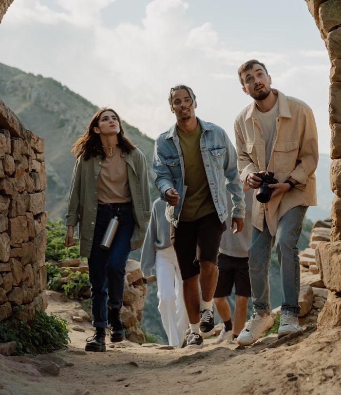 A group of young tourists exploring ancient stone ruins under a brick archway.